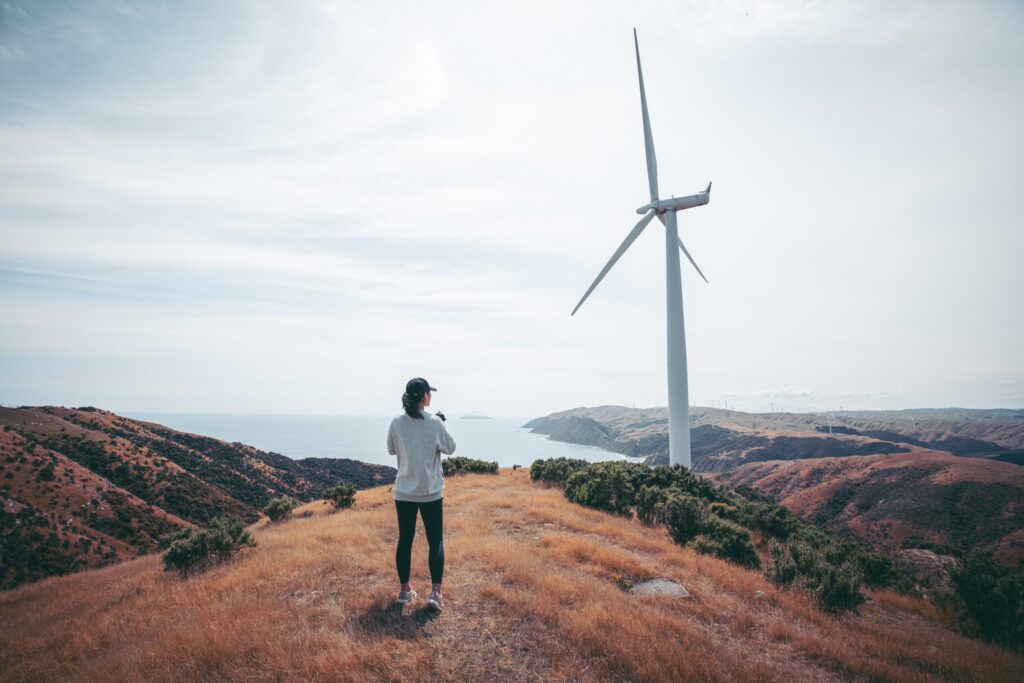 woman looking out over water and wind turbine