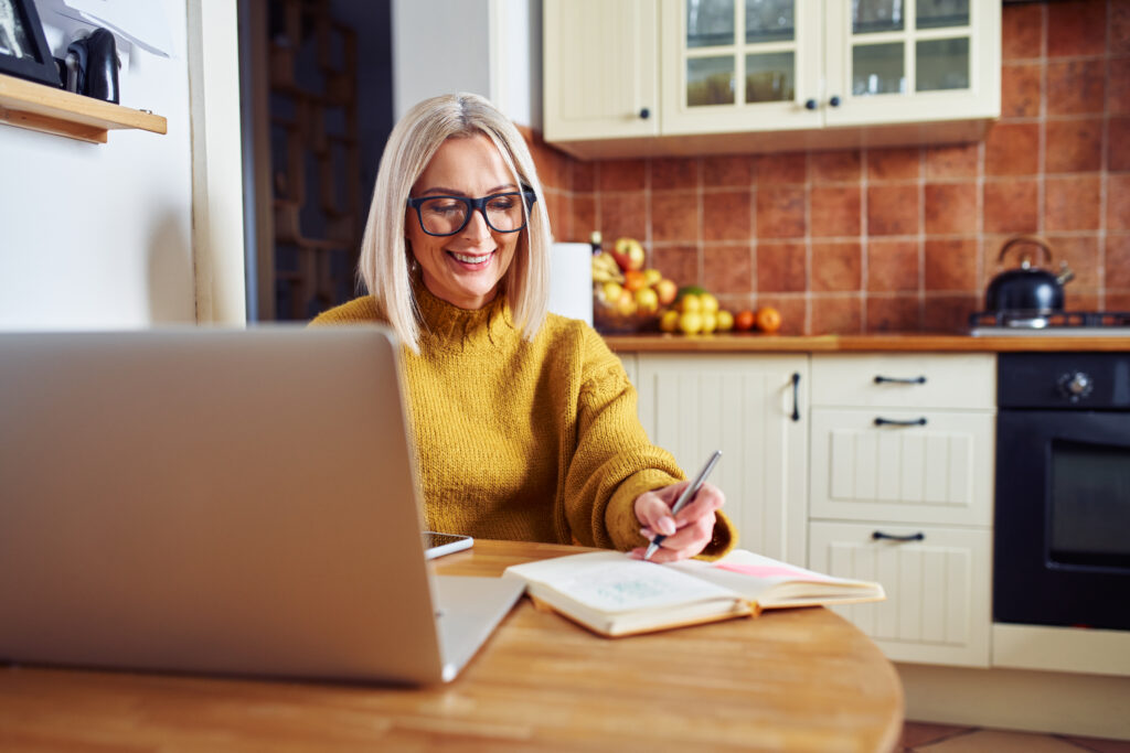 Smiling woman making notes while calculating home finances